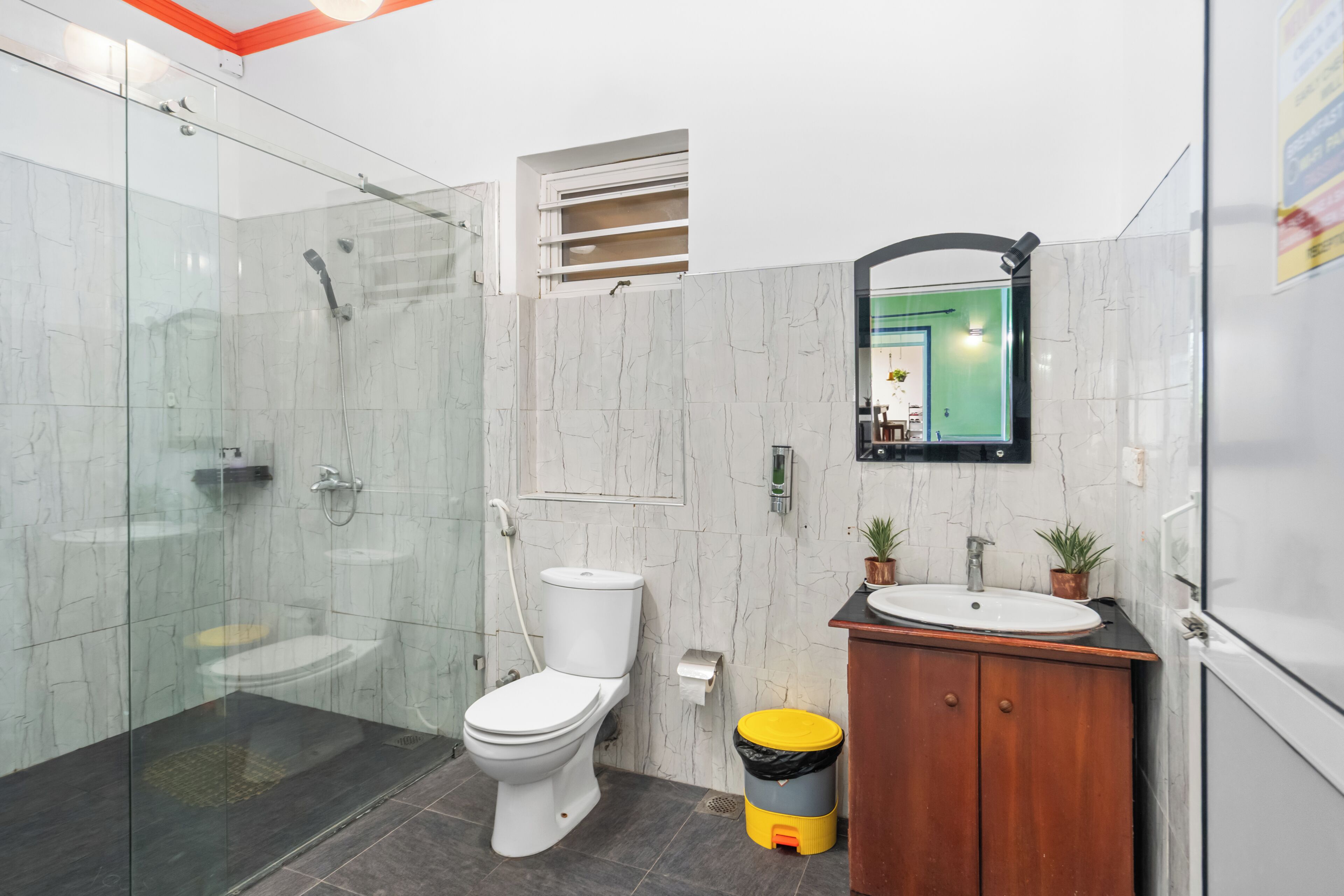 A modern bathroom with a glass-enclosed shower, a toilet, a sink with a mirror, and a wooden cabinet.