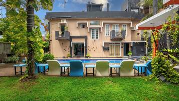 Un edificio con piscina, mobiliario exterior y un césped bien cuidado.