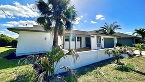 A single-story house with a white exterior, a garage, and a front yard with palm trees. - 4 bed/ 3 bath Villa Heated Pool (Cape Coral)