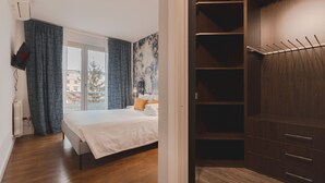 Un dormitorio con cama, armario y vistas a edificios.