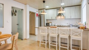 A modern kitchen with white cabinetry, a central island with bar stools, and stainless steel appliances.