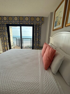 Une chambre d’hôtel avec un lit, un balcon et vue sur la mer.