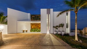 A modern building with a stone facade, a large entrance, and a well-lit interior. - Villa E11even With Private Chef Ocean Front (isla mujeres)