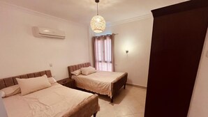 Une chambre d’hôtel avec deux lits, un ventilateur de plafond, un appareil de climatisation et une fenêtre avec des rideaux.