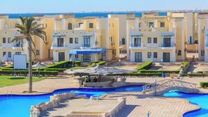 Un hôtel doté de nombreux balcons, d’une piscine et d’un palmier.