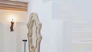 Un interior blanco con una escalera, una pieza decorativa en la pared y una lámpara de pie.