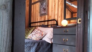 Una stanza in legno con un letto, una cassettiera e un quadro appeso al muro.