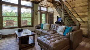 A cozy living room with a leather sofa, a wooden table, and a staircase.