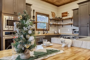 Una cocina moderna con gabinetes de madera, electrodomésticos de acero inoxidable y un árbol de Navidad decorado.