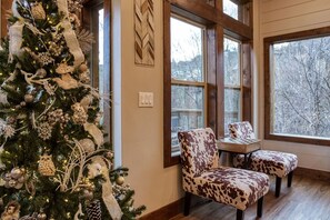 A cozy room with a large window, a Christmas tree, and two leopard print chairs. - Brand New Modern Mountain Chalet (Gatlinburg)