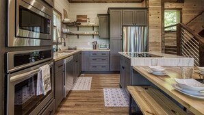 A modern kitchen with stainless steel appliances, wooden flooring, and a built-in island with a sink.
