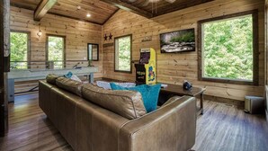 A cabin interior with a wooden ceiling, a leather sofa, a small table, and a large window.