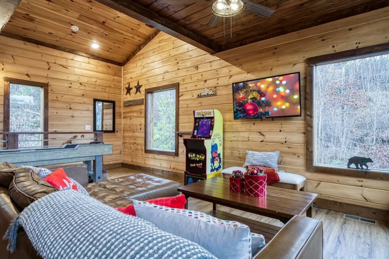 A cozy cabin interior with a wooden interior, a sofa, a table, and a gaming console.