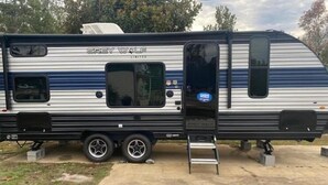 Ein Wohnmobil von Grey Wolf mit Schiebetür, kleinem Fenster und einer Auffahrtrampe für Barrierefreiheit.