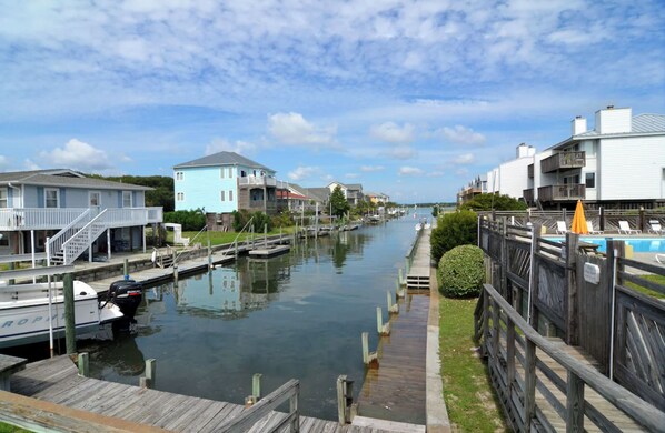 Un canal bordé de maisons de chaque côté, un quai avec un bateau et une passerelle en bois.