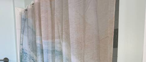 A bathroom with a shower curtain featuring a blue and beige abstract pattern.