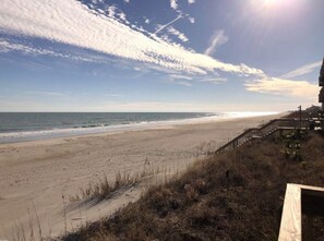 A beach with a wooden boardwalk leading to a building.
