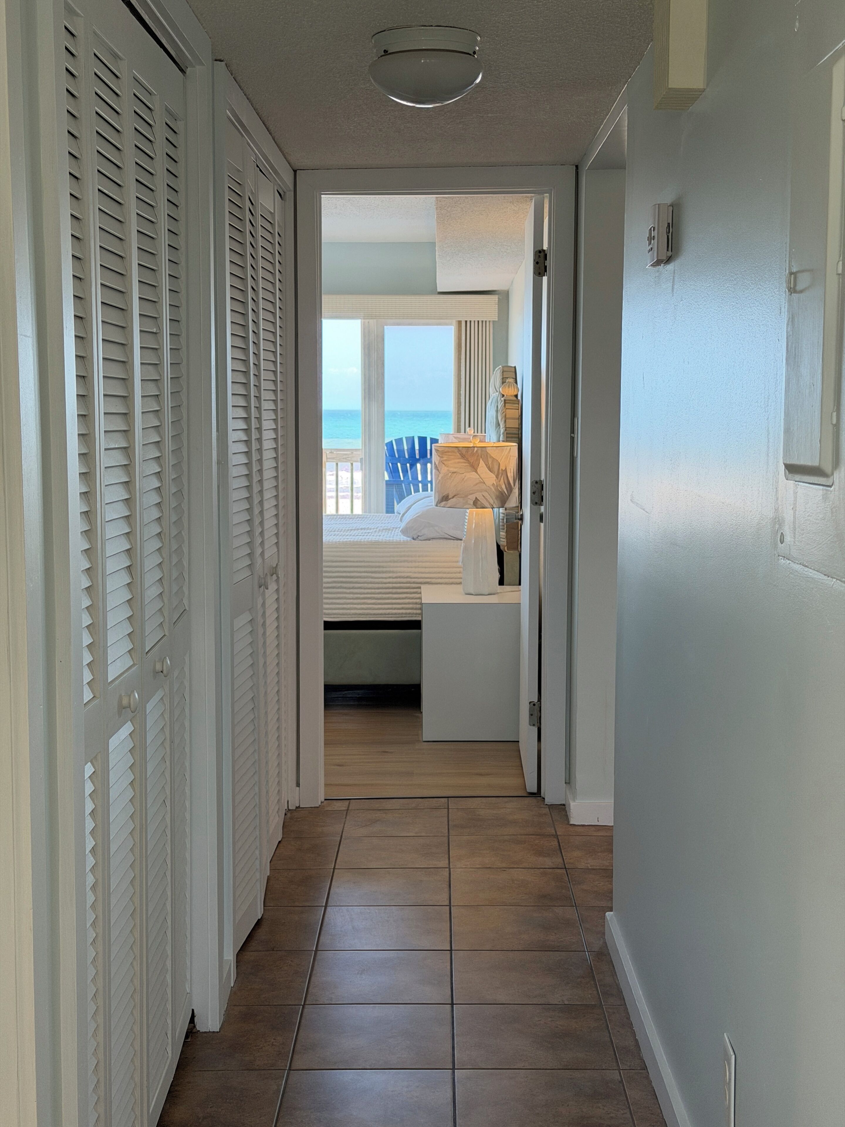 A hallway leading to a bedroom with a view of the ocean.