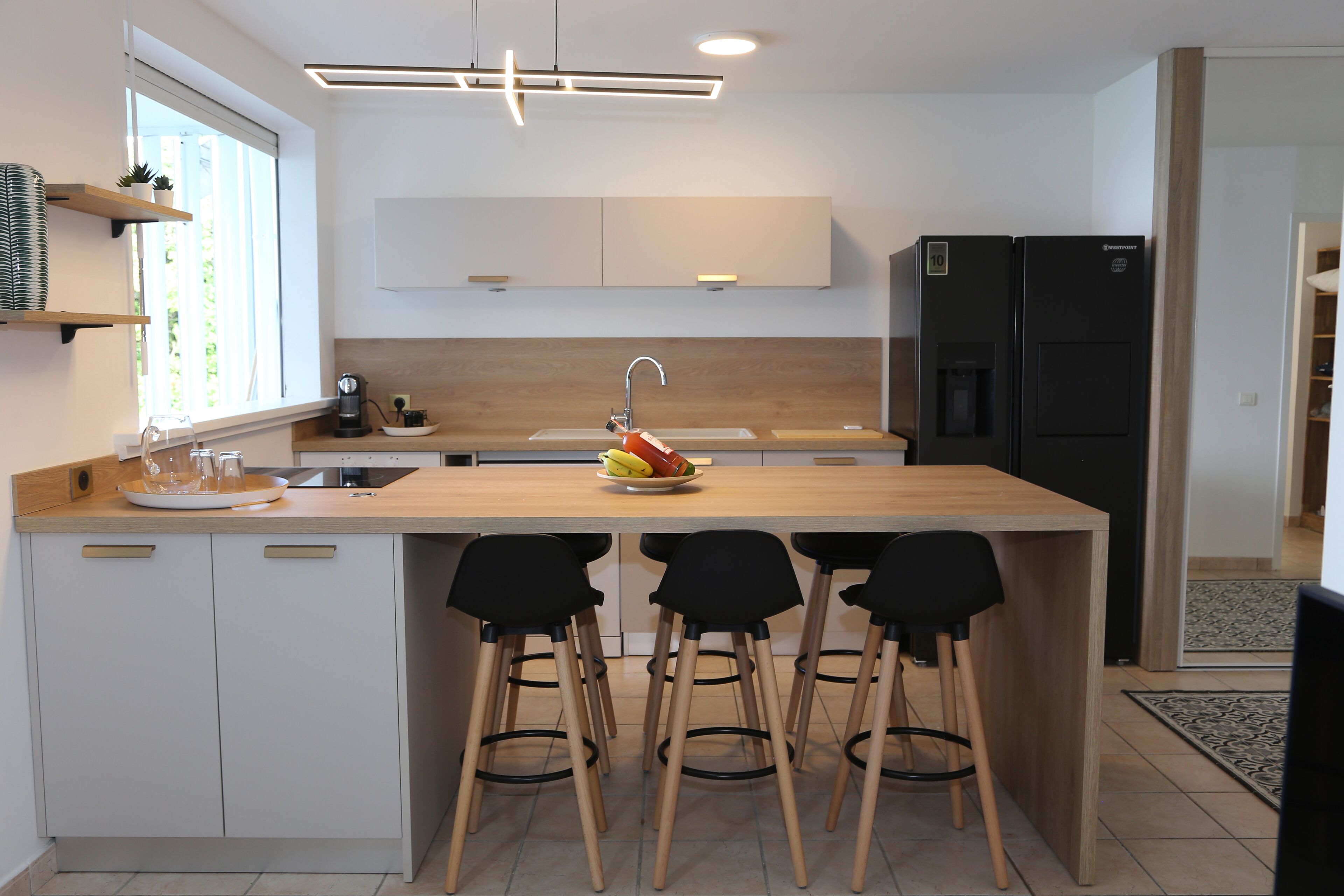 Una cucina moderna con isola centrale, sgabelli da bar, forno integrato e frigorifero.