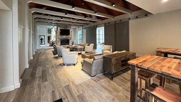 A spacious living area with a high ceiling, wooden beams, and a long view into the kitchen.