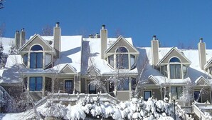 A row of three-story houses with snow-covered roofs and a snow-covered front yard.