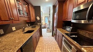 A kitchen with granite countertops, stainless steel appliances, and wooden cabinets.