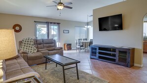 Una sala de estar con sofá, mesa de centro, televisor y comedor con mesa y sillas.