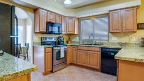 Cocina con gabinetes de madera, encimeras de granito, horno de acero inoxidable, microondas y lavavajillas.