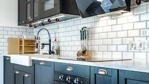 A kitchen with dark cabinets, a white tiled backsplash, and a stainless steel range hood. - Bright Apartment Near the lake (Bordeaux)