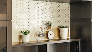 A kitchen counter with a decorative backsplash, a bicycle, a clock, and two potted plants. - Bright Apartment Near the lake (Bordeaux)