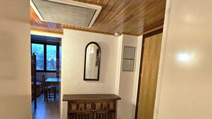 Un pasillo con un armario de madera, un espejo y una puerta.