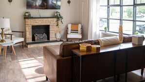 A living room with a fireplace, a sofa, a coffee table, and a TV mounted on the wall. - Pet Friendly 3 bedroom 1 king,1 Queen,1 Full Bed Home (Youngstown)