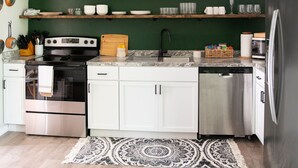 A modern kitchen with white cabinets, a stainless steel refrigerator, and a green accent wall. - Pet Friendly 3 bedroom 1 king,1 Queen,1 Full Bed Home (Youngstown)