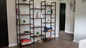A corner with two black metal shelving units, each holding books, decorative items, and small plants. - Pet Friendly 3 bedroom 1 king,1 Queen,1 Full Bed Home (Youngstown)