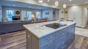 A spacious living room with a large TV, a dining area with a chandelier, and a kitchen with a marble countertop.