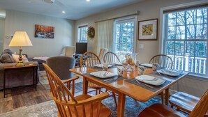 A dining area with a wooden table set for four, surrounded by wooden chairs.