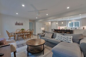 A modern living room with a sofa, coffee table, and dining area with chairs. - Rock Haven Lake Vacation Rental | Peaceful Waterfront Escape with Dock, Kayaks & Pet-Friendly Comfort (Newfield)