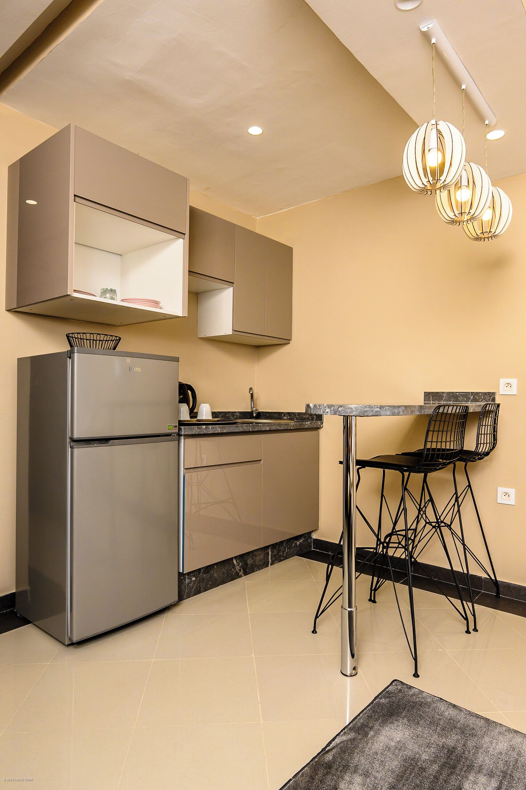 Una cocina compacta con refrigerador, estufa y un comedor con sillas y mesa.