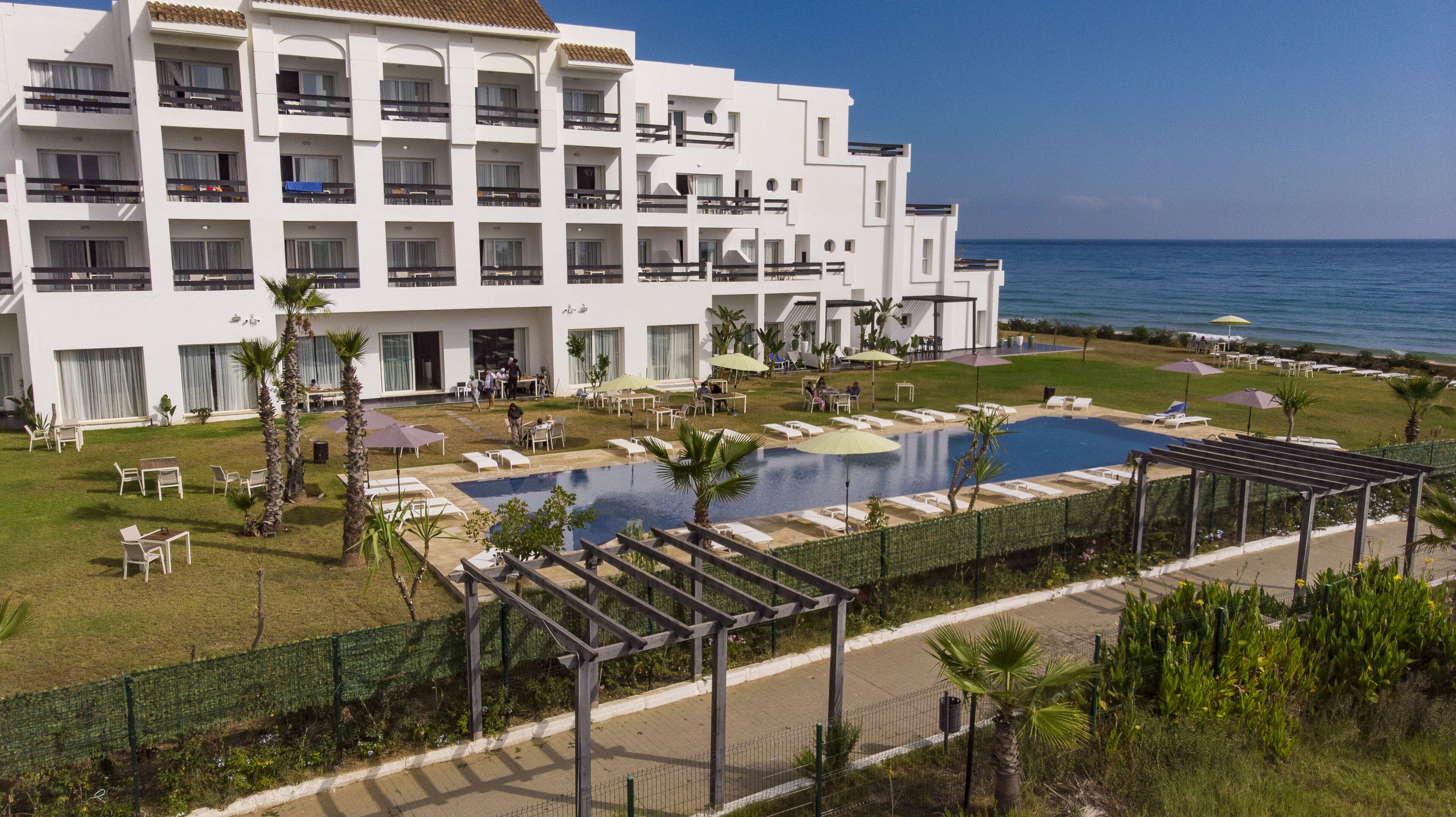Un hotel con piscina, mobiliario exterior y vista al mar.