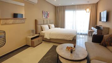 Quarto de hotel moderno com uma cama grande, uma escrivaninha, um sofá e uma mesa de jantar com comida.