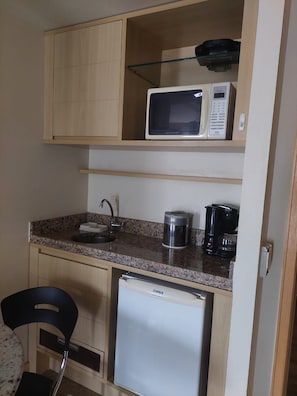 Une petite cuisine équipée d’un four à micro-ondes, d’une machine à café et d’un mini-réfrigérateur.