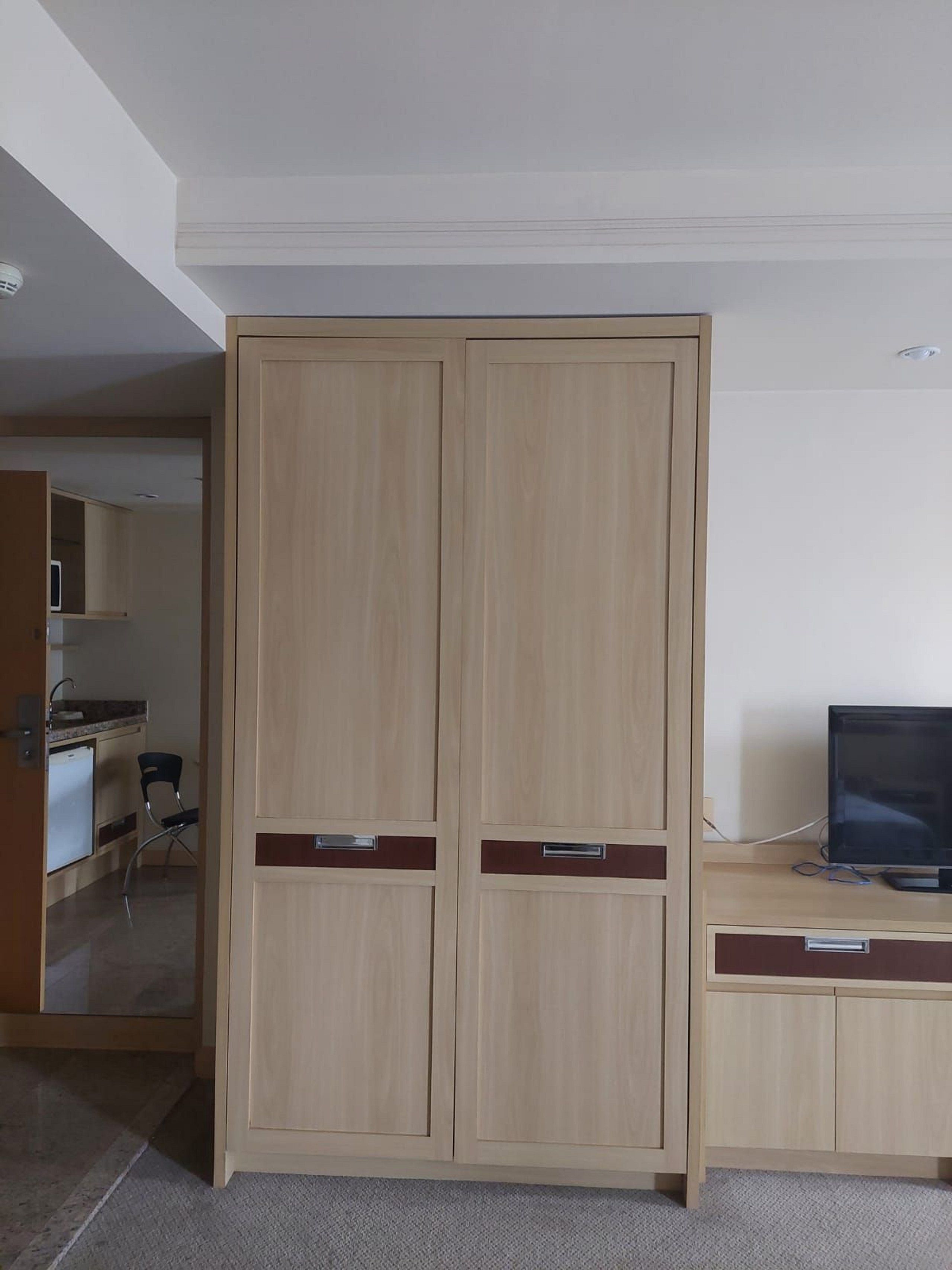 Une pièce comprenant une armoire en bois, un bureau avec un ordinateur et une chaise.