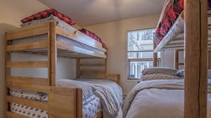 Une chambre avec un lit superposé, composé de deux lits, chacun doté d’une structure en bois et d’une literie grise.