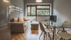 A modern living room with a sofa, ottoman, and glass dining table with chairs. - San Pietro Cozy And Quiet Three-room Apt (Rome)
