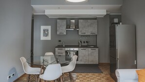 A modern kitchen with grey cabinets, a glass dining table, and white chairs. - San Pietro Cozy And Quiet Three-room Apt (Rome)