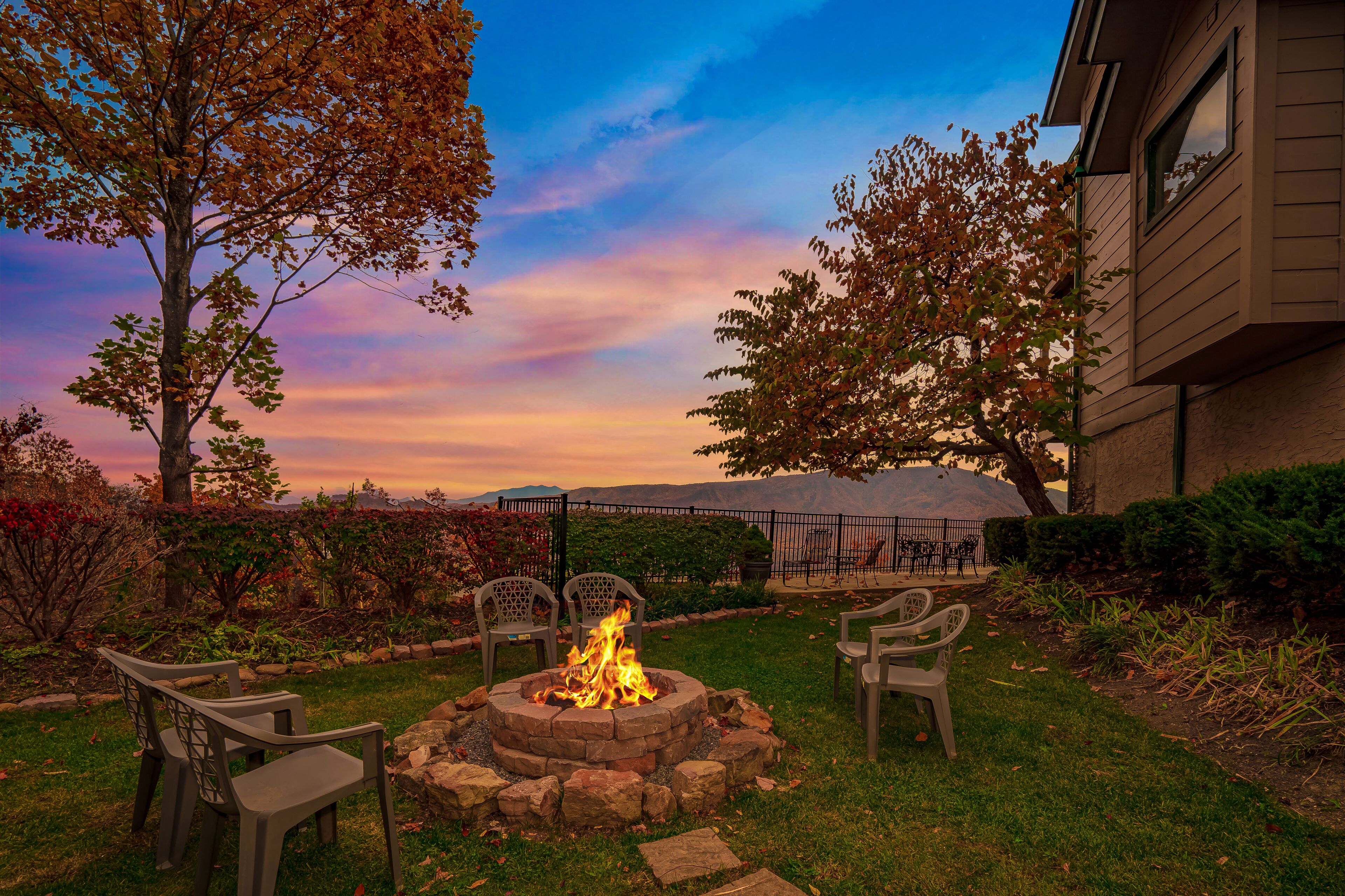 Un jardin avec un foyer extérieur, des chaises de jardin et une vue sur une chaîne de montagnes.