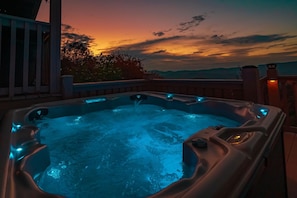 Un jacuzzi con luces azules en una terraza con vista al atardecer.