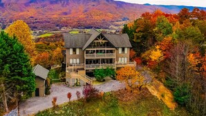 A two-story building with a balcony, surrounded by autumn-colored trees and a mountainous backdrop.