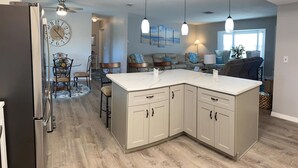 A modern kitchen with a large island, wooden flooring, and pendant lighting. - Serenity now, full refund*, pool heat, sleeps 8 (Rotonda West)