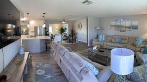 A modern living room with a grey sofa, a coffee table, and a dining area with a round table and chairs. - Serenity now, full refund*, pool heat, sleeps 8 (Rotonda West)